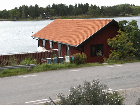 Rött båthus vid strandkanten